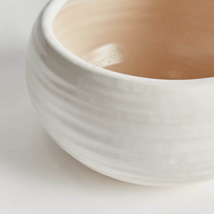 Side profile of wide stoneware bowl with rounded silhouette and subtle ridging in reactive oatmeal glaze.