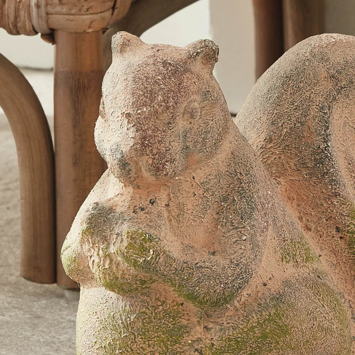 Handcrafted terracotta squirrel figurine with curled tail and green moss finish, photographed at a three-quarter angle.

