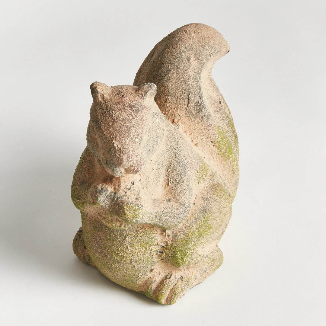 Top-down angle of moss terracotta squirrel sculpture, showing its seated form, large tail, and natural stone-like texture.

