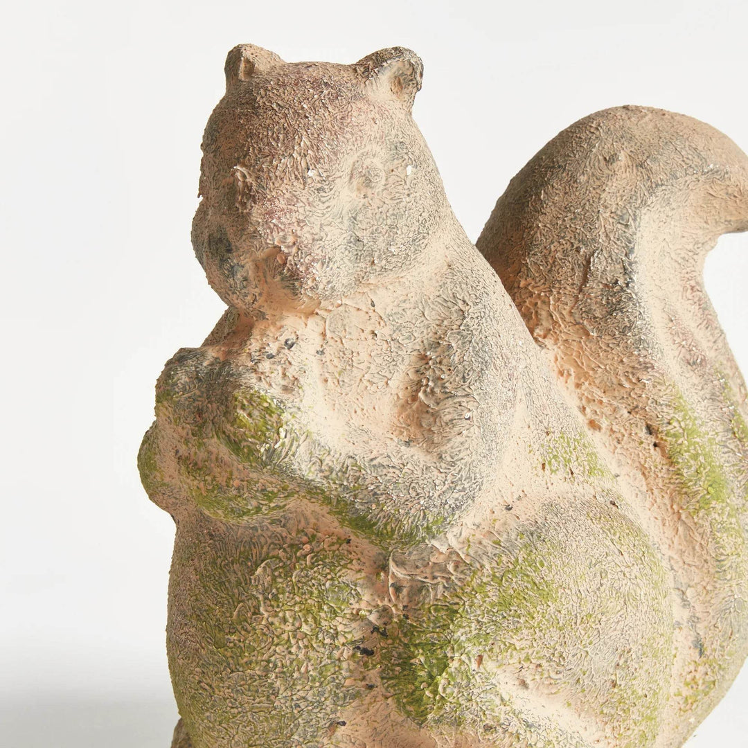 Back view of weathered terracotta garden squirrel with moss accents and coarse surface texture, highlighting handmade variation.

