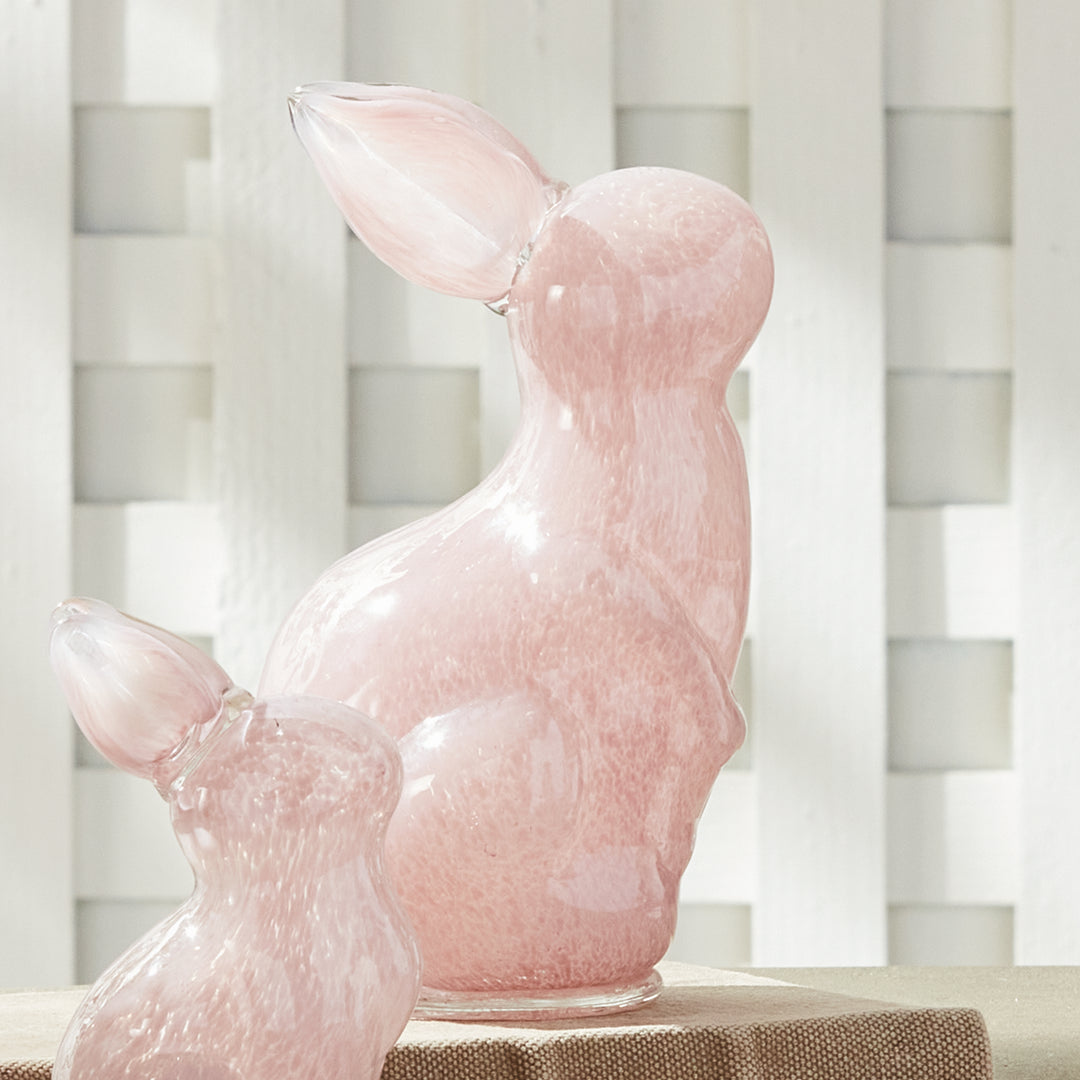 Pink glass bunny on a table with a white lattice background