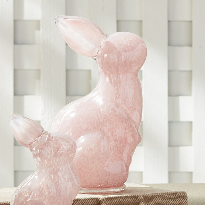 Pink glass bunny on a table with a white lattice background
