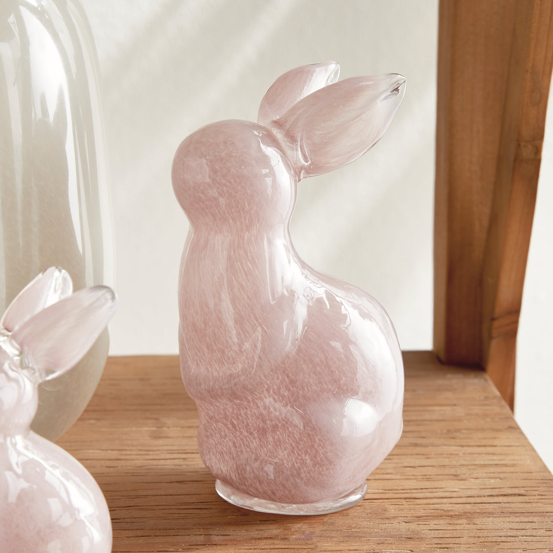 Pink rabbit sculpture on a wooden surface with a blurred background