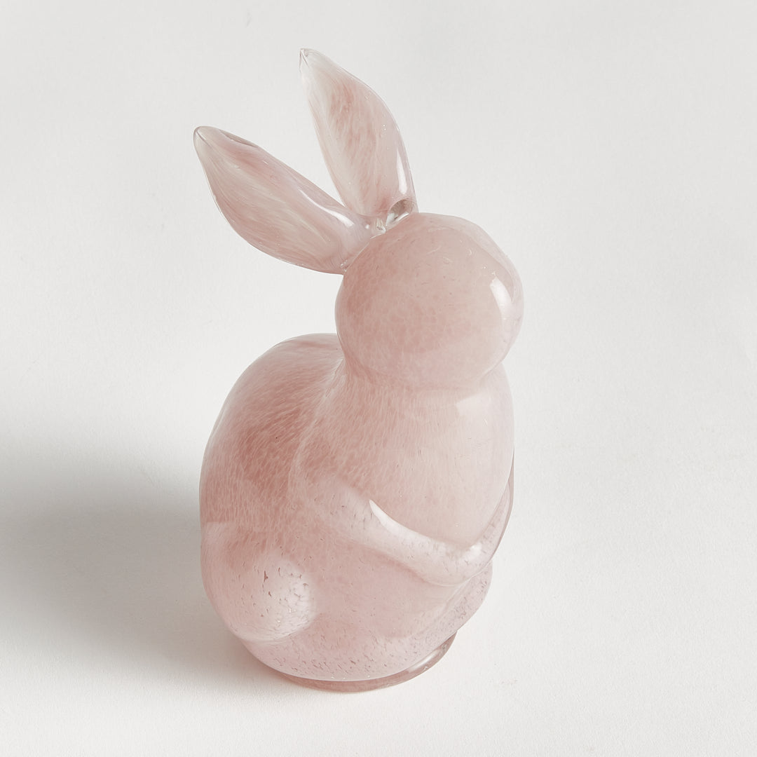 Pink glass rabbit figurine on a light gray background