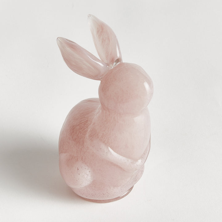 Pink glass rabbit figurine on a light gray background