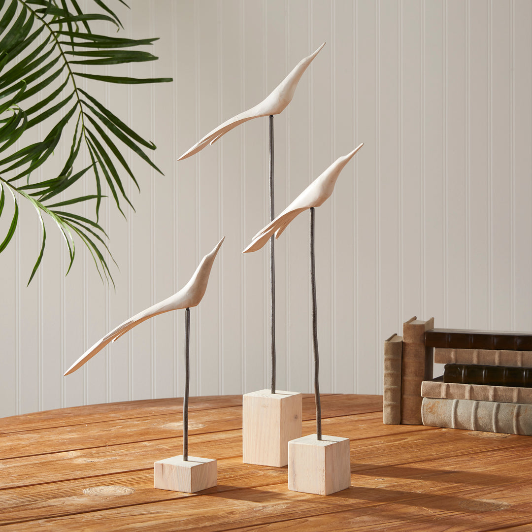 Decorative bird sculptures on a wooden surface with a neutral background