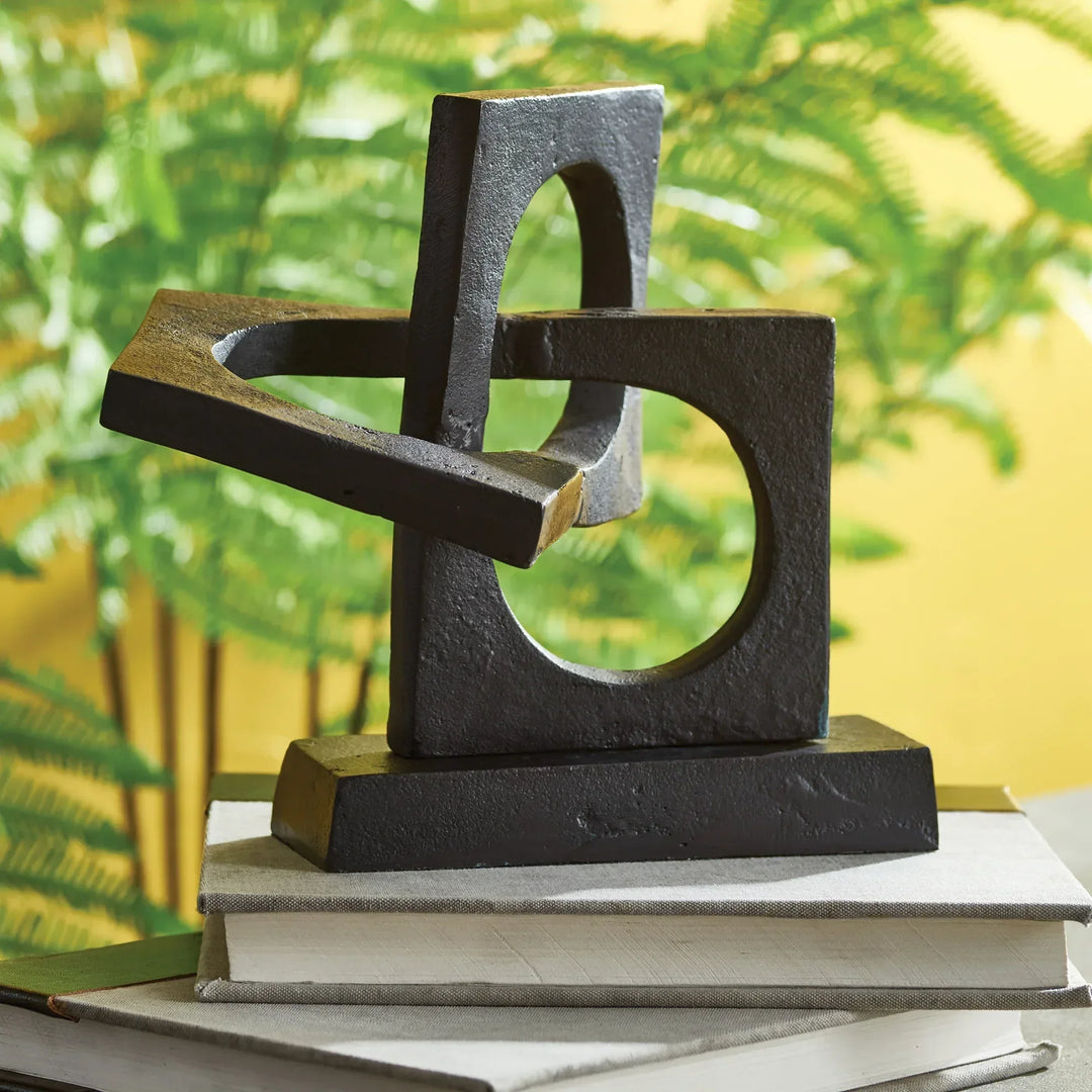 Abstract metal sculpture on books with a blurred green and yellow background