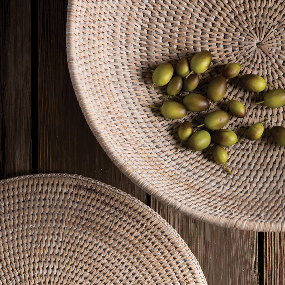 Overhead close-up of whitewash woven rattan offering bowl with green fruit showing the intricate interior weave, Transitional