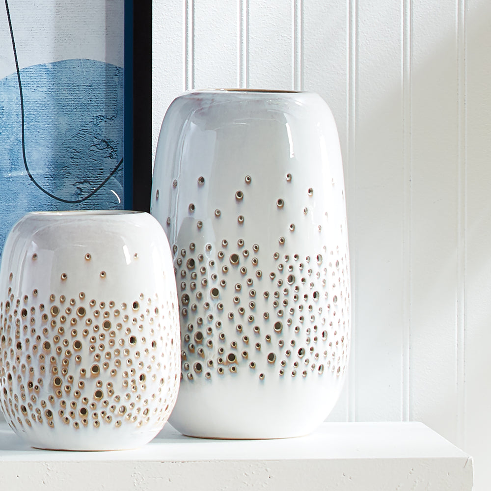 Illuminate your home with sophistication and elegance using these beautifully crafted candleholders. The effervescence of bubbles in the surf is captured in the dots of light emitted from the candles within. With a creamy, high gloss glaze adding a refined touch, each candleholder exudes a radiant glow thanks to its expertly designed construction. Elevate your home decor and atmosphere with these luxurious candleholders.