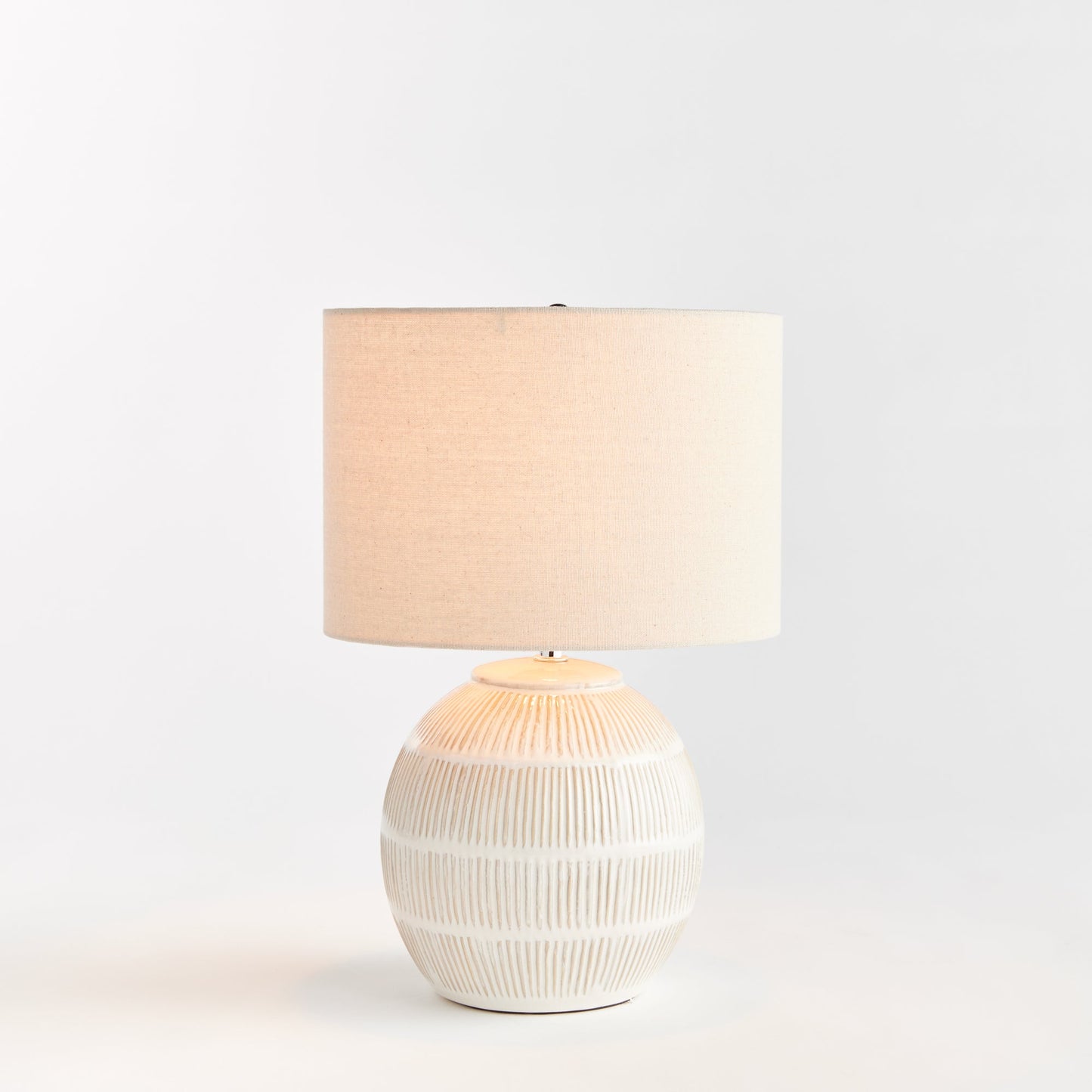 Featuring a rounded ceramic body with a hatch mark pattern, the Antoni White Table Lamp brings character to any space. The natural linen shade serves as a lovely accent on a bedside table, side table, or desk in a living room or dining area.