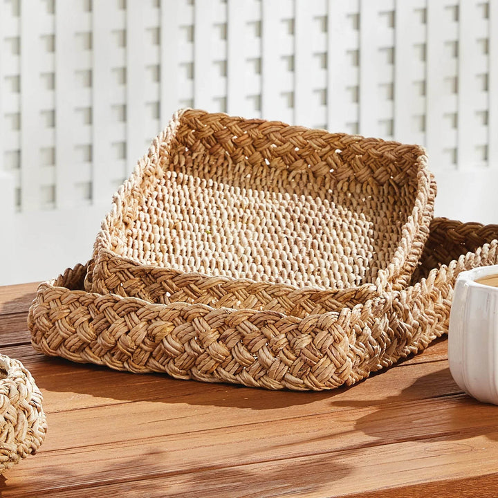Set of abaca French braided rectangular trays displayed on wooden table with decorative accents