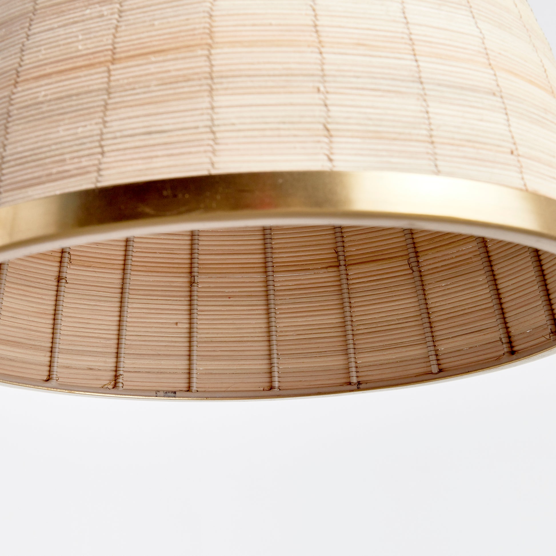 Experience the timeless style of the Maye Petite Bell Pendant Light in white, featuring a natural cane rattan weave with unique variations in color. The brass details on the top and bottom rim add a refined touch to this classic piece. Whether hung in a kitchen, entryway, or hallway, this pendant light will elevate any space with its sophisticated charm.