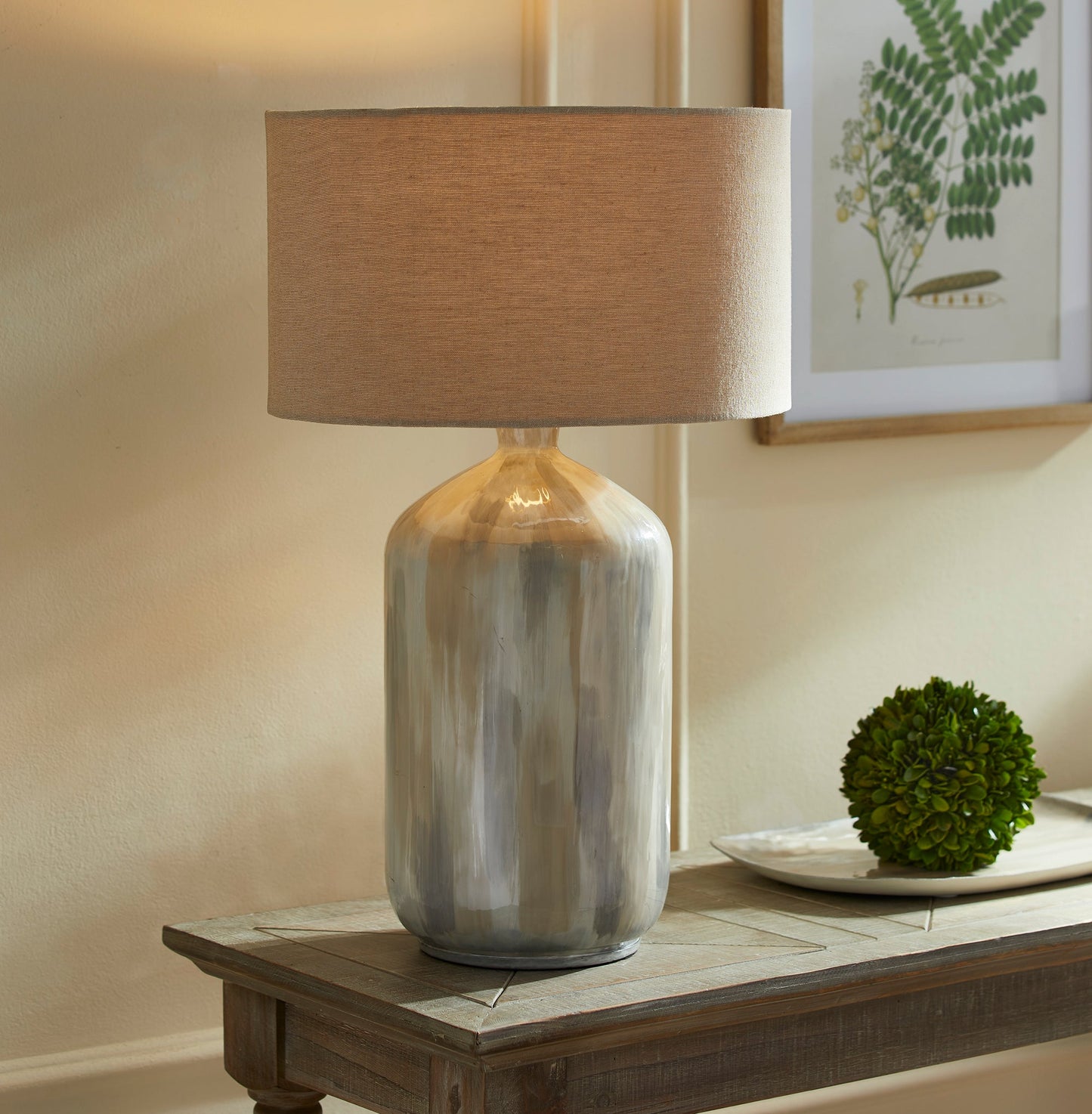 Hand-painted with enameled iron, this lightweight beauty boasts a neutral, creamy tone-on-tone design. Each lamp is meticulously crafted, making it a stunning addition to any contemporary living area. Finished off with an oversized linen shade, this table lamp offers both style and function.