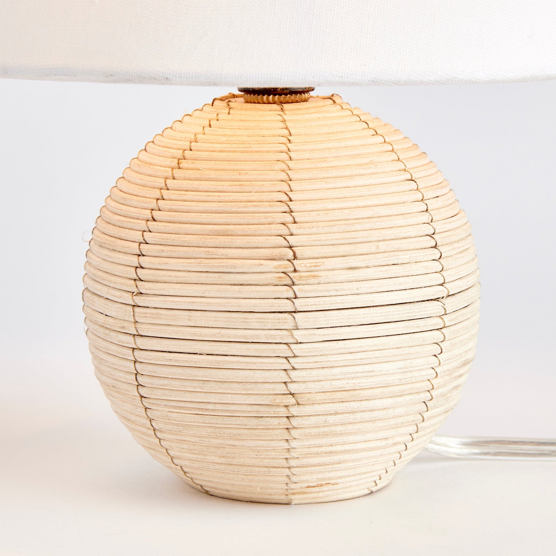 Handcrafted with natural cane rattan, every mini table lamp displays unique variations in color, making it truly one-of-a-kind. Its compact size and refined cotton blend shade make it an ideal choice for kitchens or small workspaces. Featuring natural tones and rattan material, it is a perfect addition to any bedroom.