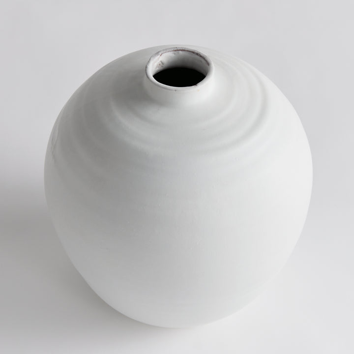 Enhance your decor with the Andorra White Pot Vase. Featuring a unique ribbed design and a smooth, matte white glaze, this vase adds a touch of elegance to any room. Use faux stems or leave it as is for a cleaner look. With its soft subtle ribbing, it brings in a light and neutral accent, making it a must-have for any decor.