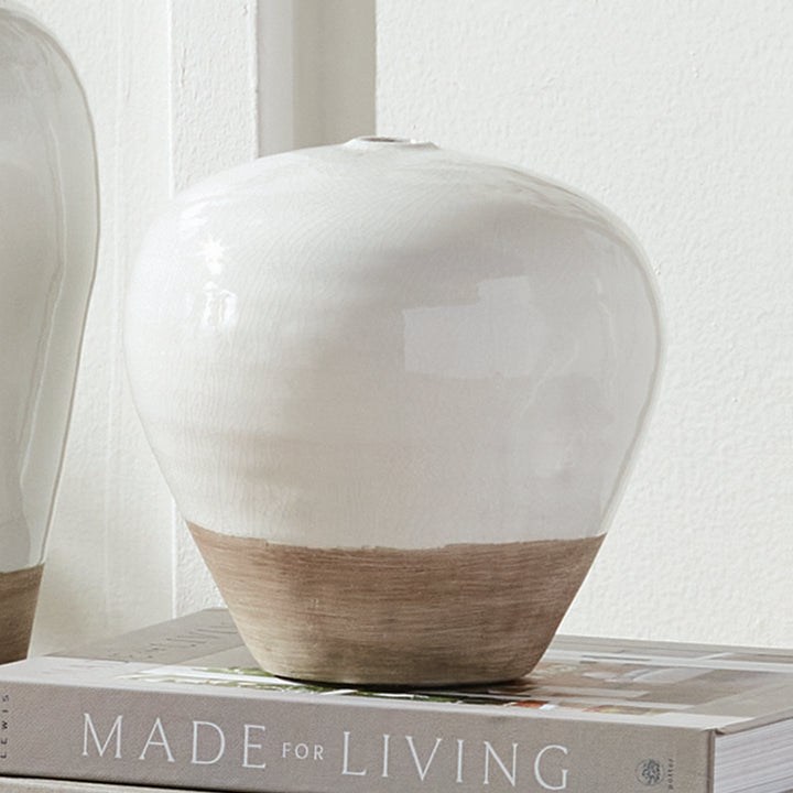 Alba small white terracotta vase styled on a book stack beside the matching large vase against a paneled wall. Modern Organic