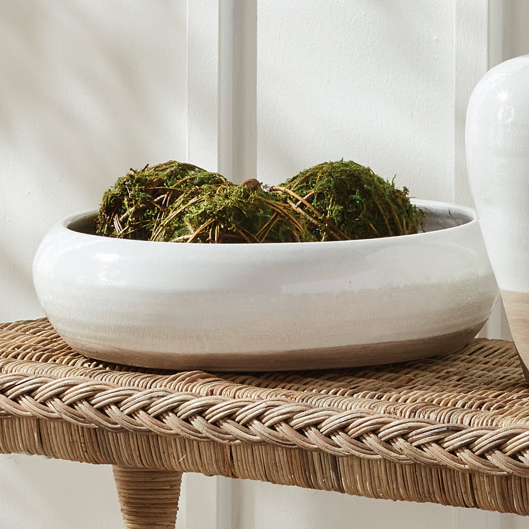 Alba white bowl with moss-covered decorative orbs on woven furniture beside a matching white vase in a room. Modern Organic