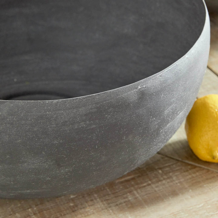 Close-up of decorative metal bowl with aged zinc finish and softly curved sculptural form – Industrial style.