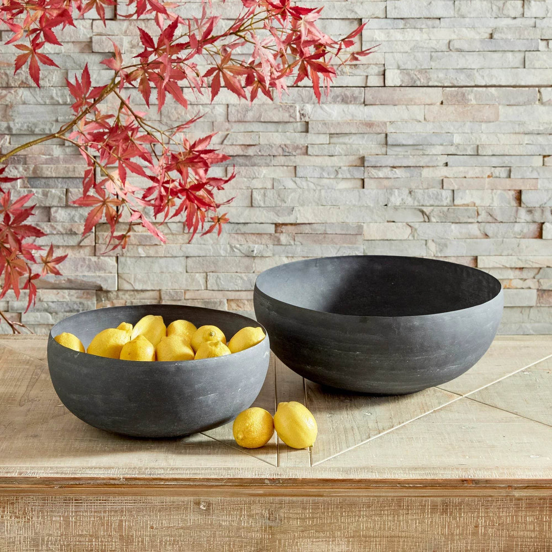 Decorative metal bowls styled with citrus accents on a tabletop with layered natural textures – Transitional style.