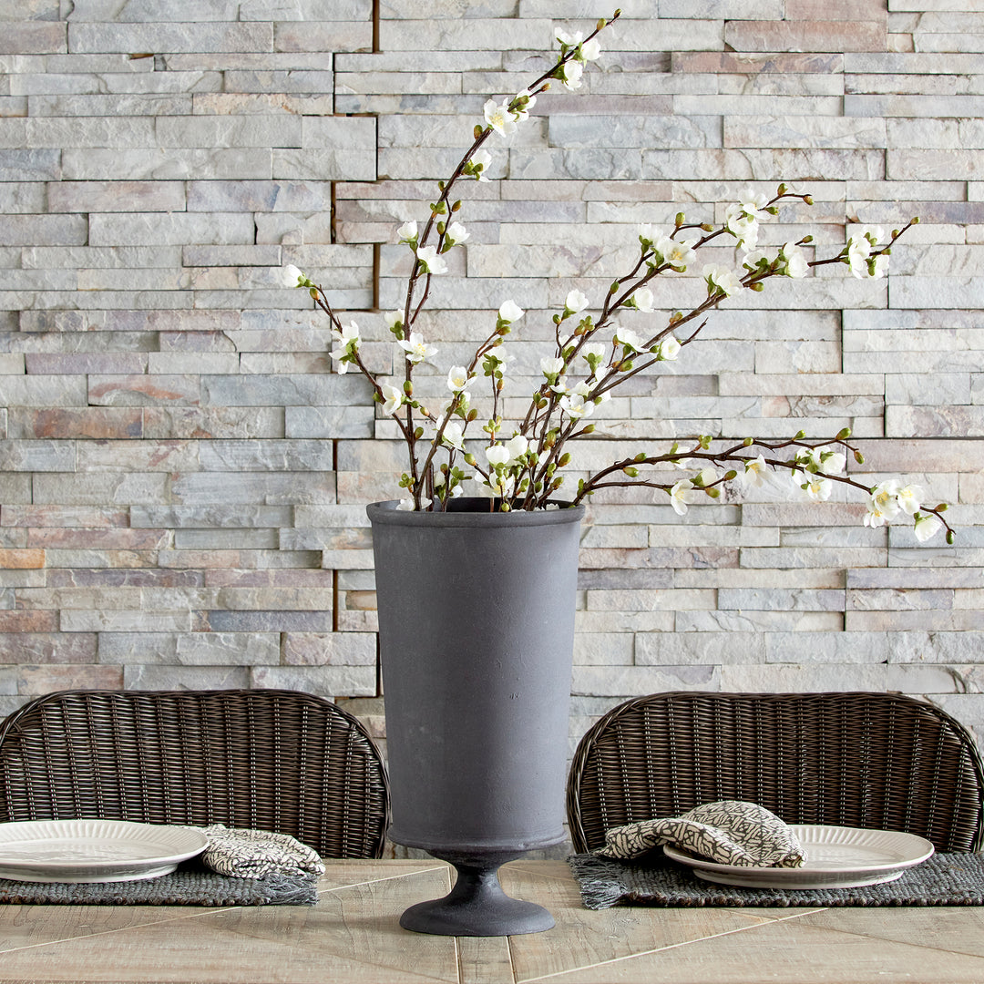 Aged zinc decorative metal urn vase with faux branches on dining table in European garden style