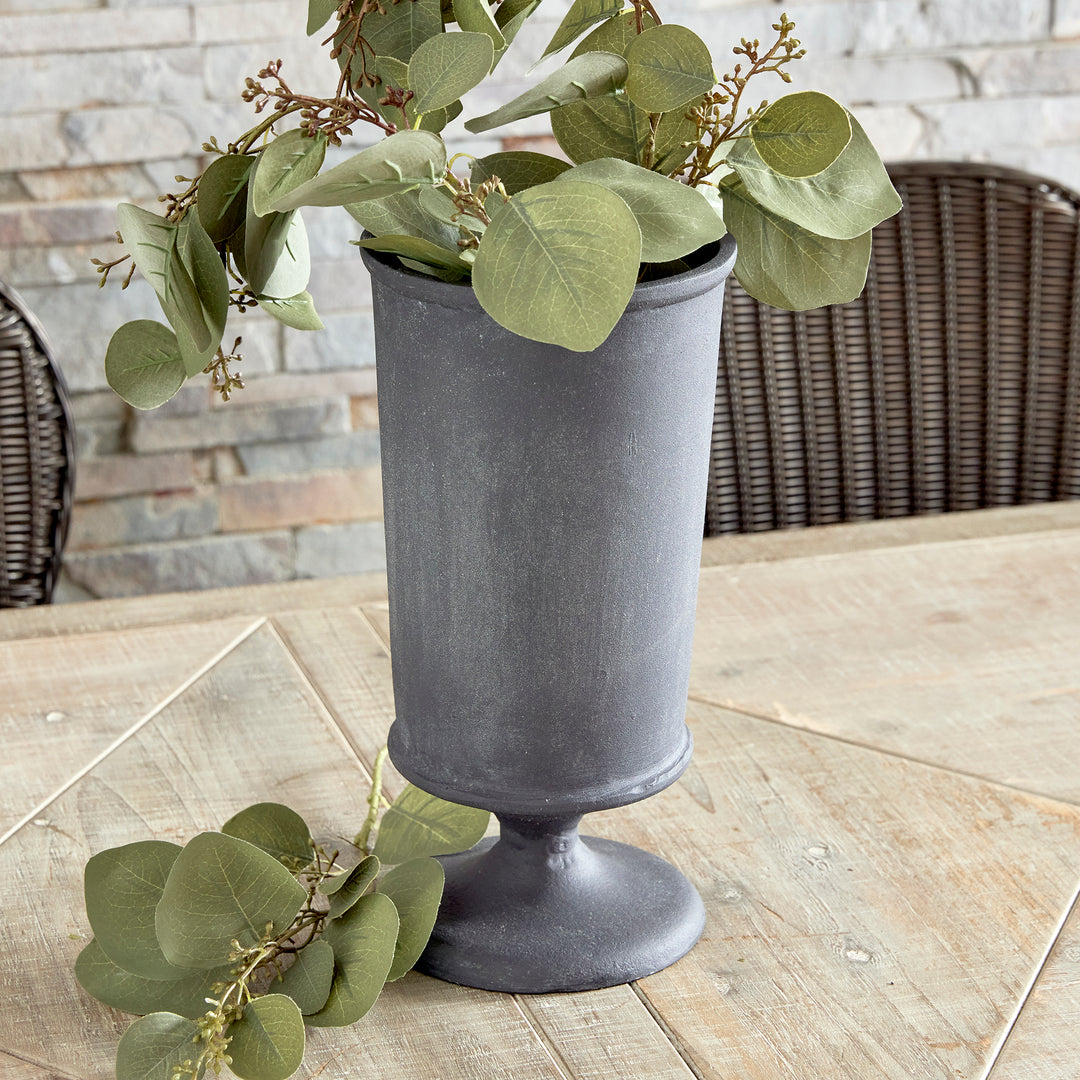 Decorative metal urn vase with faux stems and sculptural pedestal silhouette in transitional style
