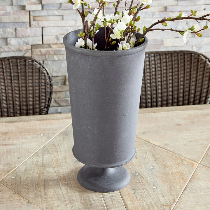 Small decorative metal urn vase with pedestal base styled on tabletop in transitional interior style