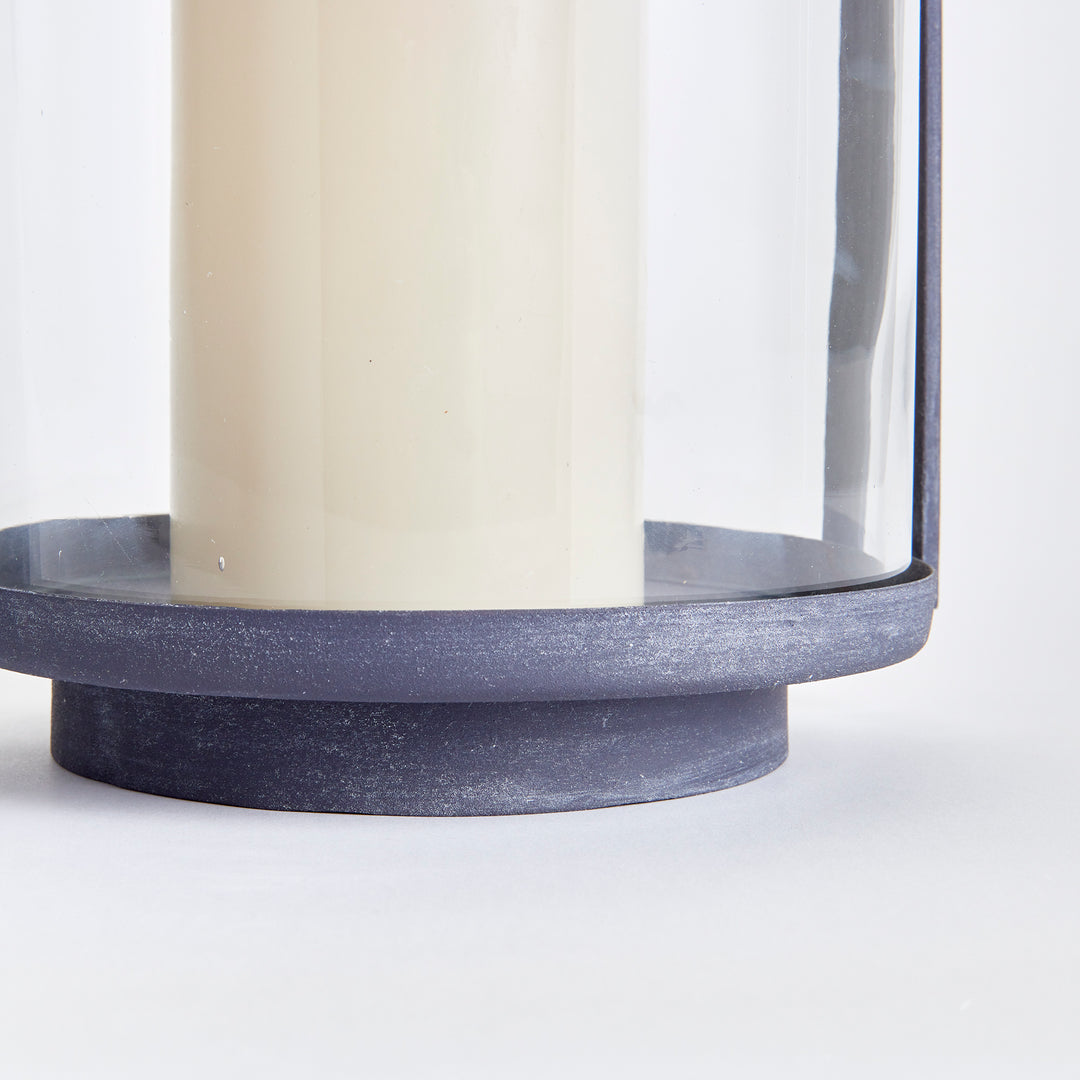 Close-up of outdoor hurricane candle holder base with aged zinc finish and minimalist metal construction – Modern Organic style.