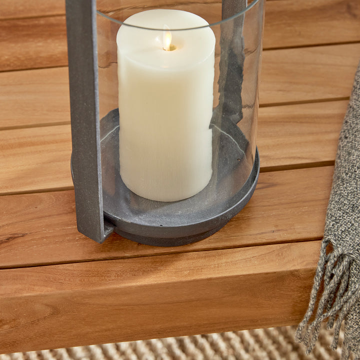 Detail view of outdoor hurricane candle holder with aged zinc base and clear glass hurricane cylinder – Industrial Outdoor style.