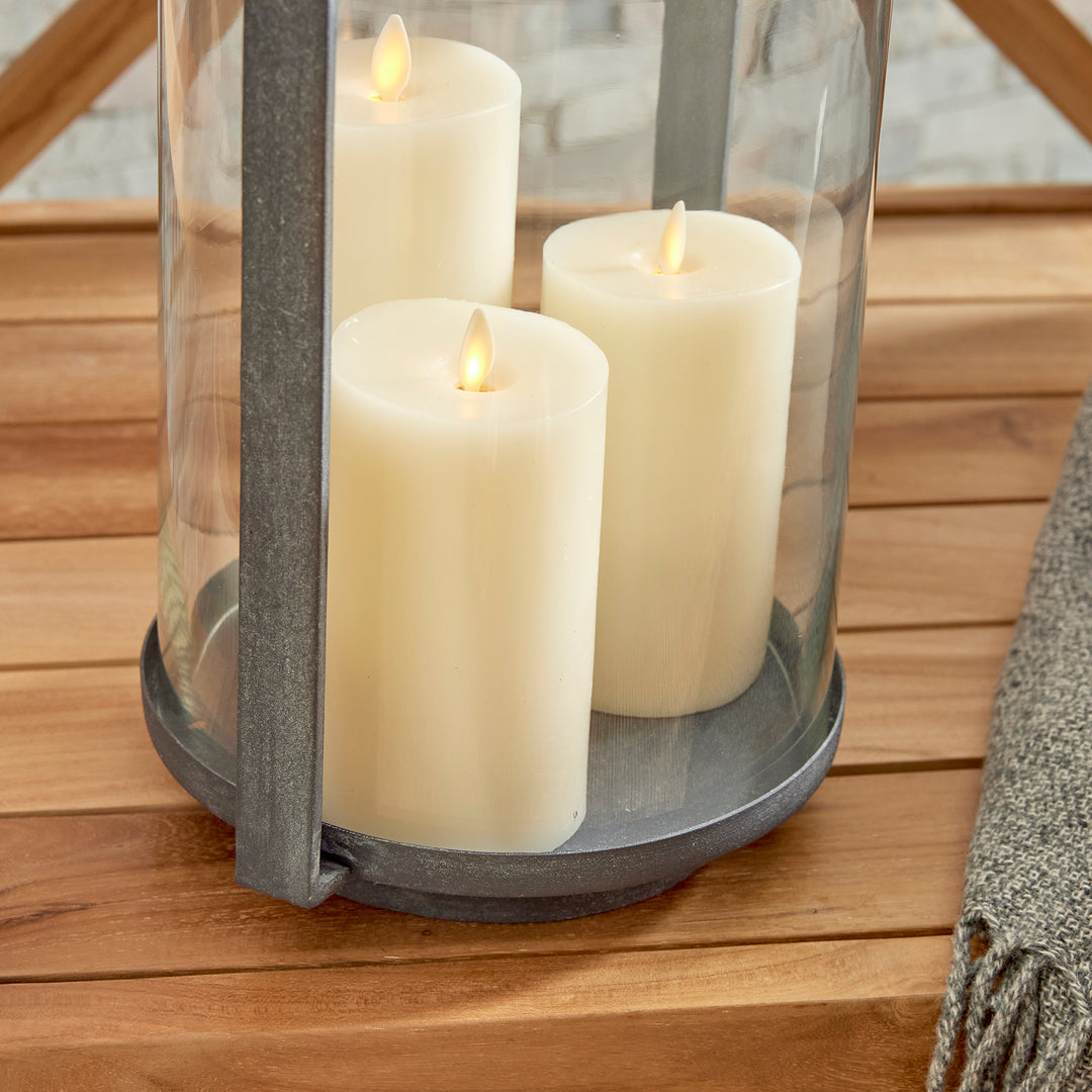 Outdoor hurricane candle holder with clear glass cylinder and warm candlelight styled on a wood surface – Transitional style.