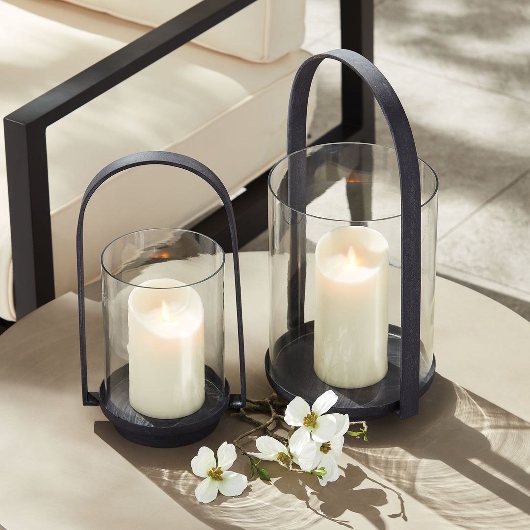 Outdoor hurricane candle holders styled together beside seating with warm candlelight and aged zinc metal frames – European Garden style.