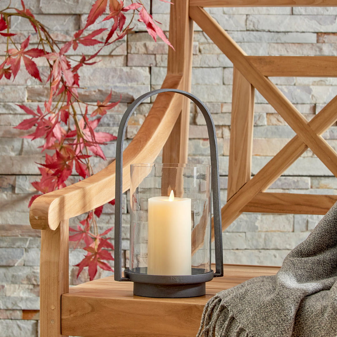 Outdoor hurricane candle holder styled on a covered patio with layered candlelight and natural wood accents – European Garden style.