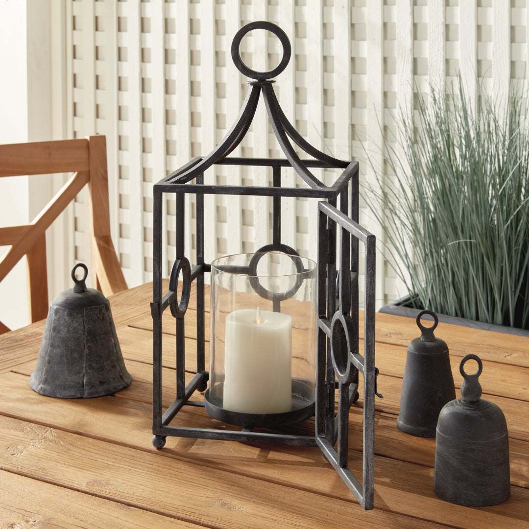 Iron outdoor candle holder with glass hurricane insert styled in a covered outdoor seating area – Modern Farmhouse style.