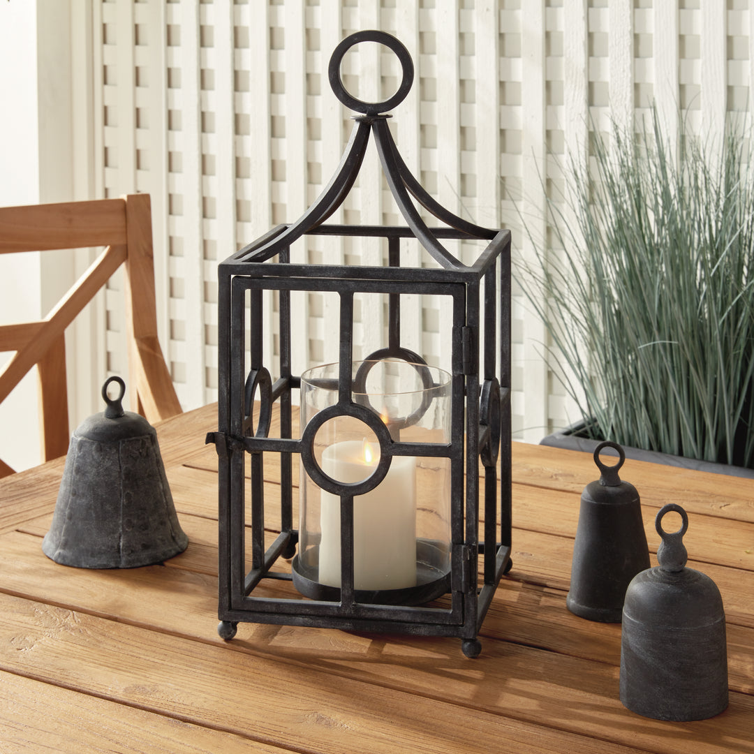 Outdoor metal candle holder styled on a wood deck with layered lantern decor and aged zinc finish – Transitional style.