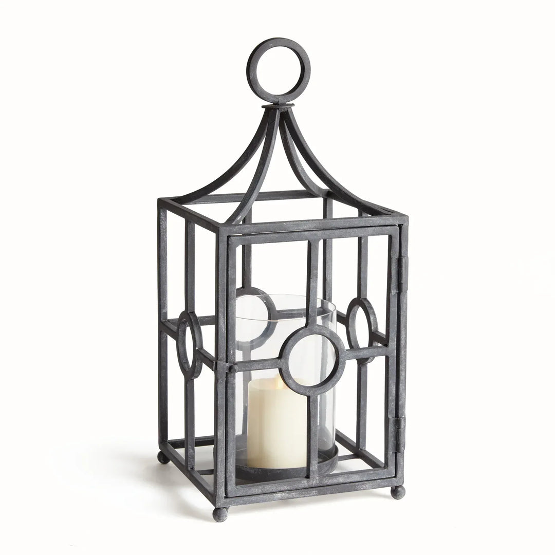 Outdoor metal candle holder with aged zinc finish, geometric iron frame, and glass hurricane insert for covered patios and garden-inspired spaces – European Garden style.