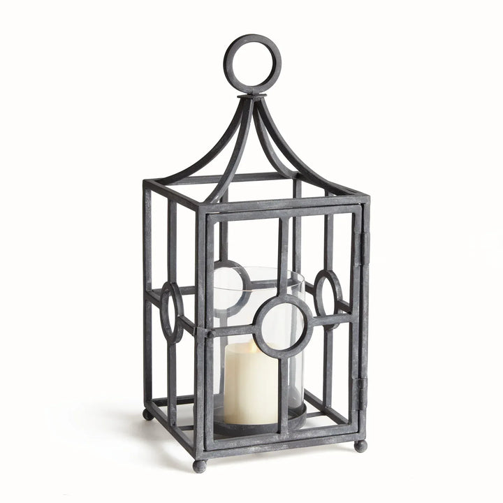 Outdoor metal candle holder with aged zinc finish, geometric iron frame, and glass hurricane insert for covered patios and garden-inspired spaces – European Garden style.