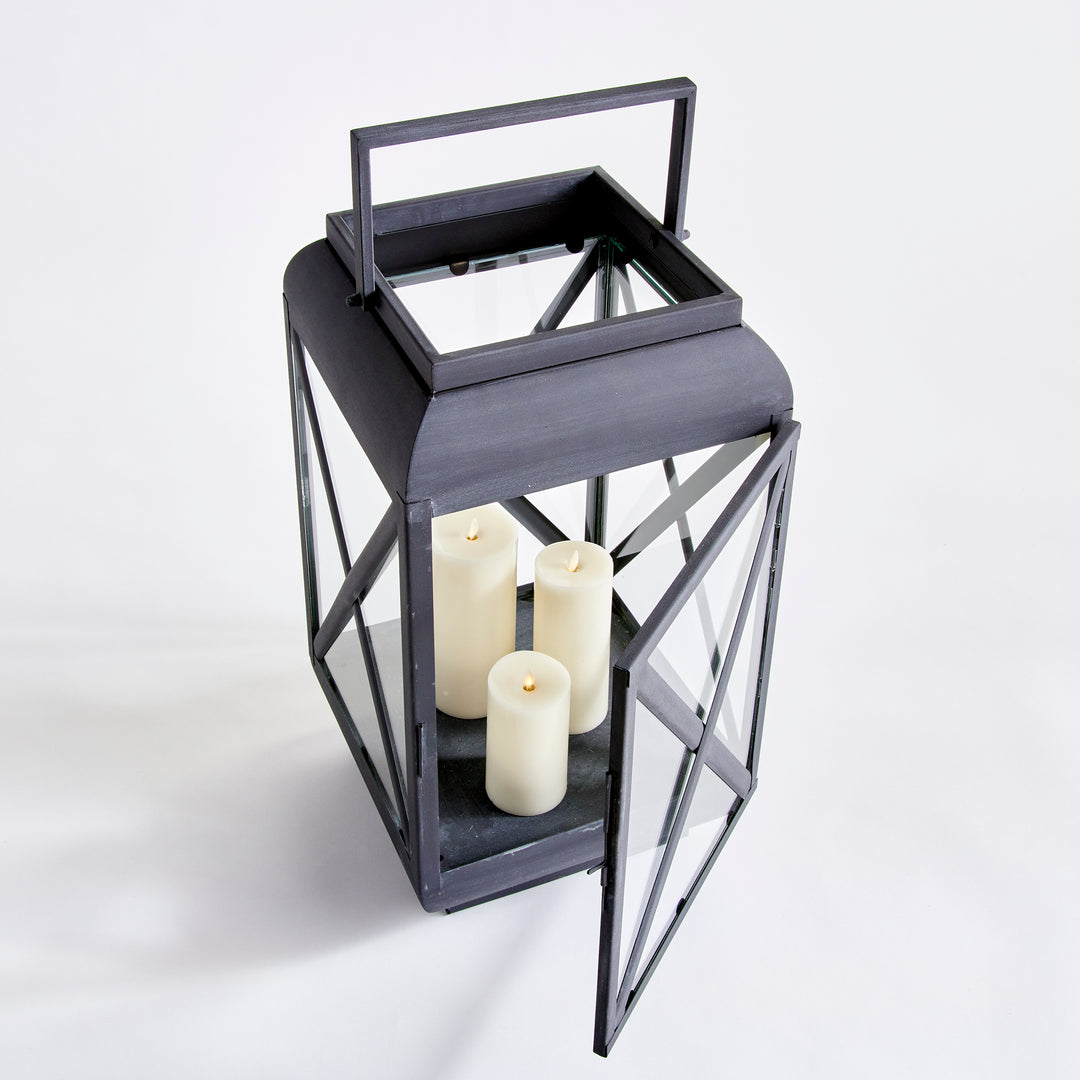 Angled outdoor metal lantern with open glass door and iron cross-brace detailing for patio styling – Industrial Outdoor style.