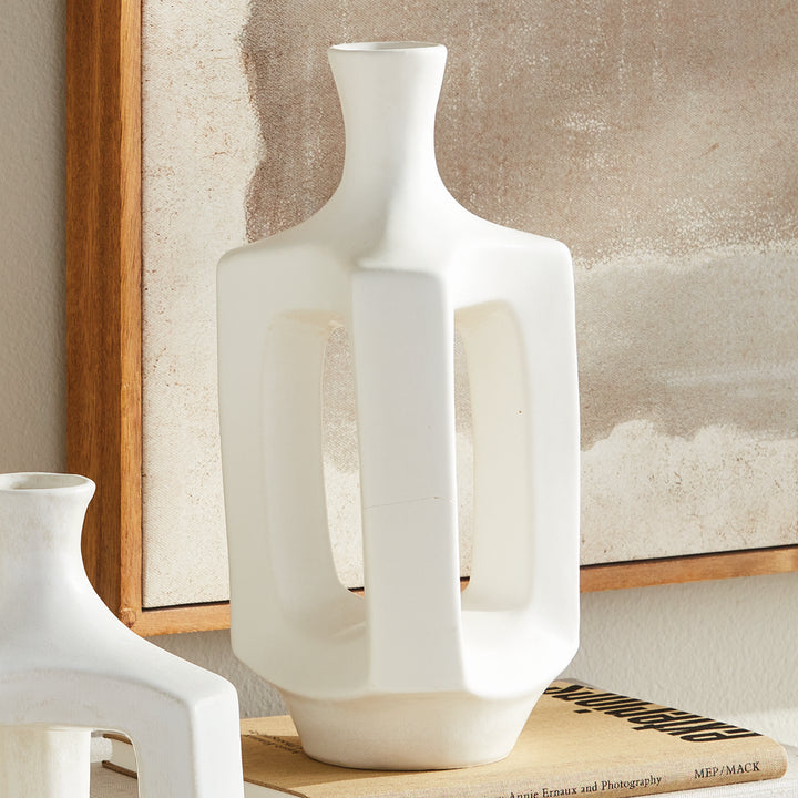 Medium matte white clay vase, styled beside coordinating white vases, with an open frame and a narrow neck. Modern Organic
