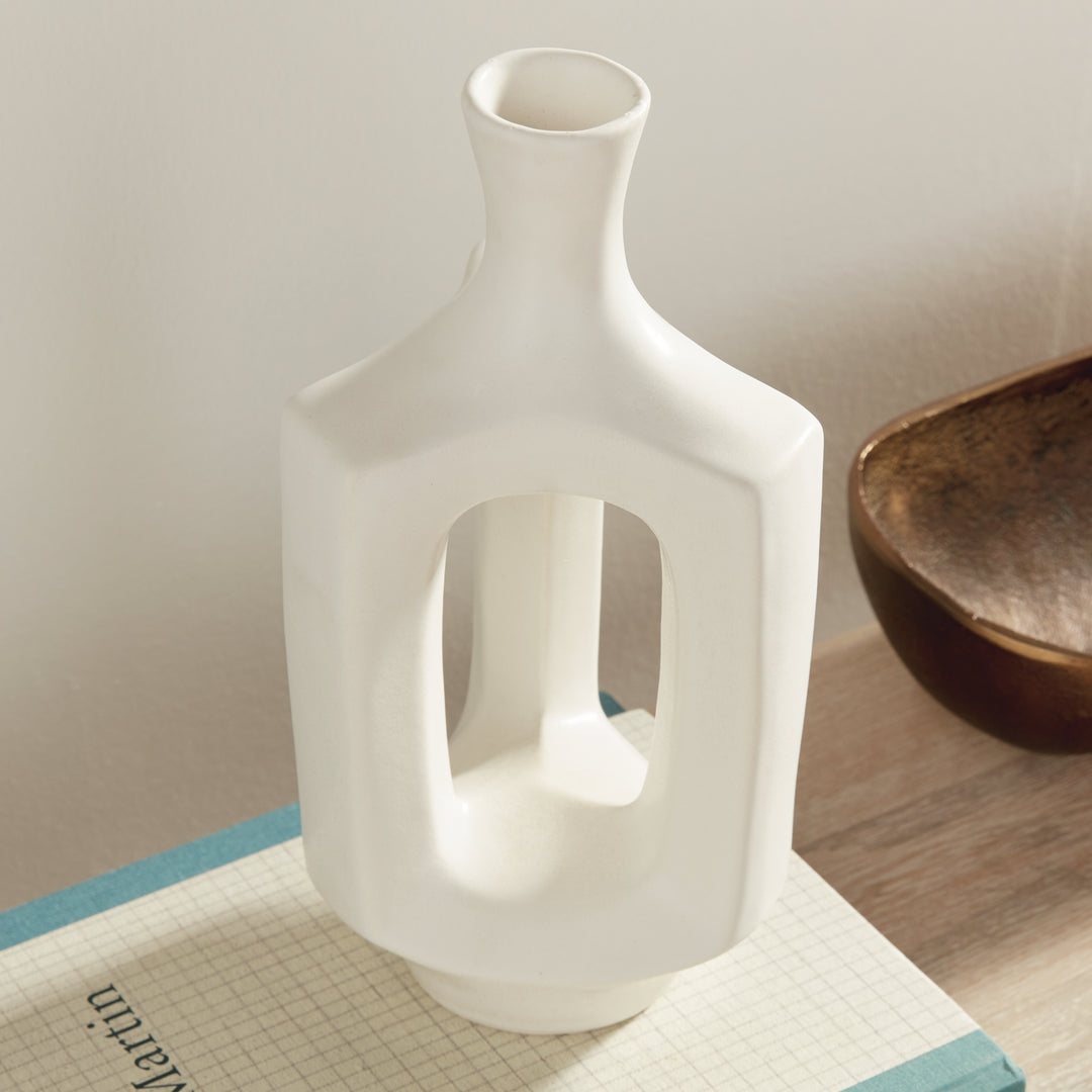 Medium matte white clay vase, angled display on books, highlighting the hollow center and softly curved neck. Modern Organic