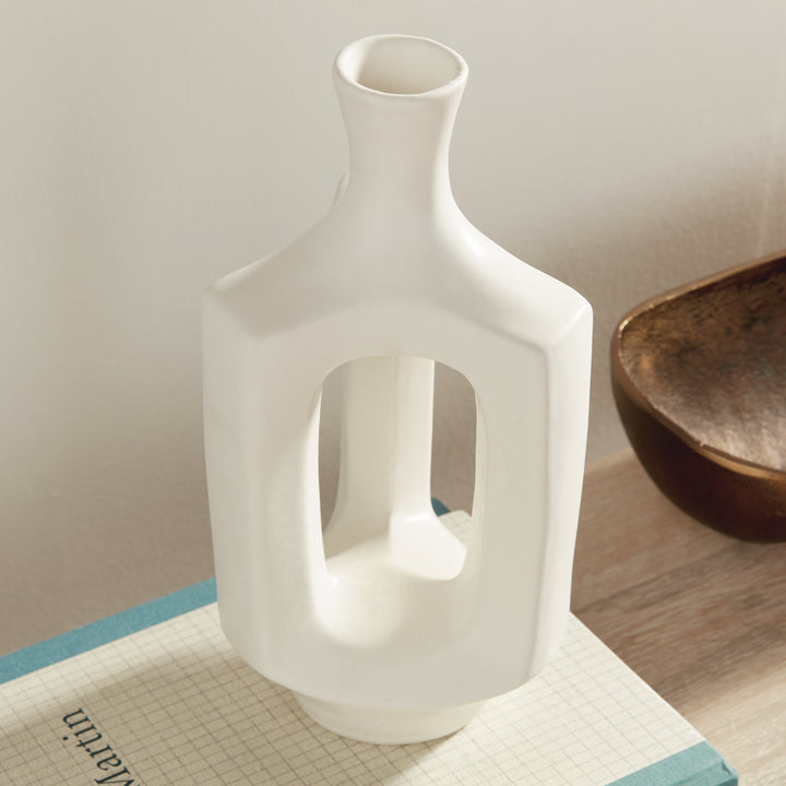 Medium matte white clay vase, angled display on books, highlighting the hollow center and softly curved neck. Modern Organic