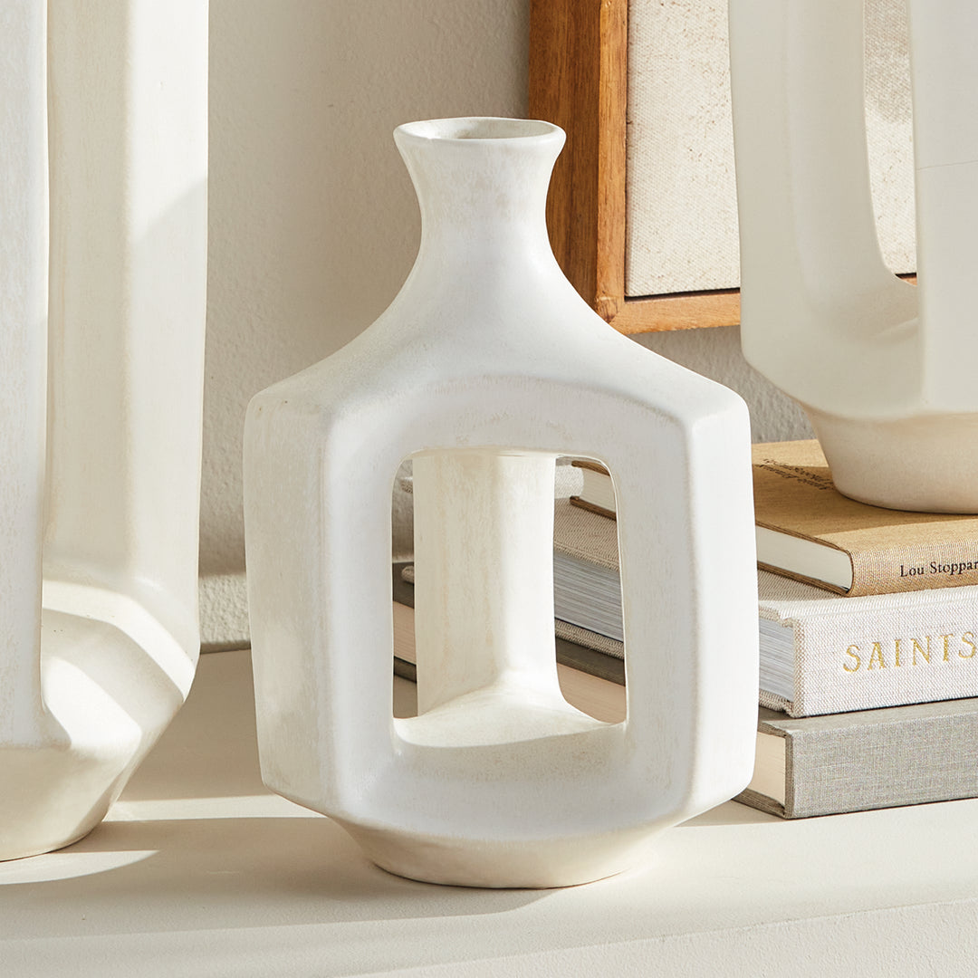 Short matte white clay vase, styled beside coordinating white vases, with an open frame and a narrow neck. Modern Organic