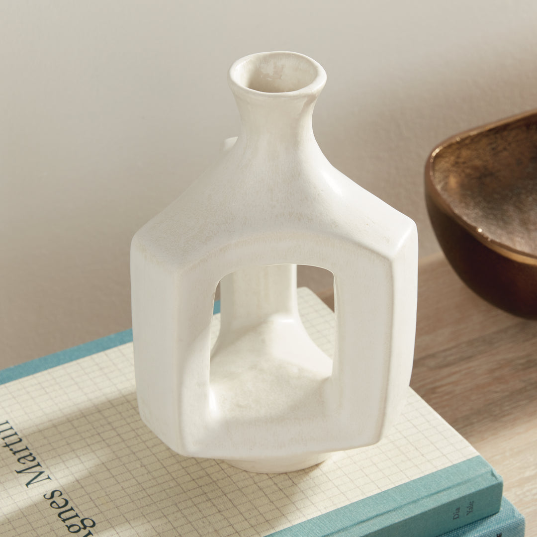 Short matte white clay vase, angled display on books, highlighting the hollow center and softly curved neck. Modern Organic