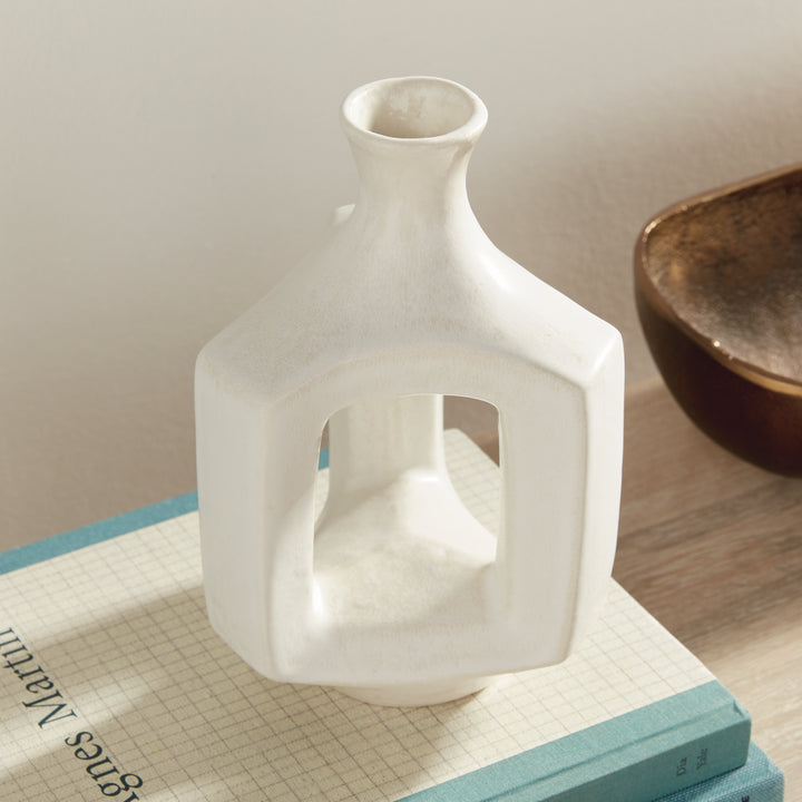 Short matte white clay vase, angled display on books, highlighting the hollow center and softly curved neck. Modern Organic