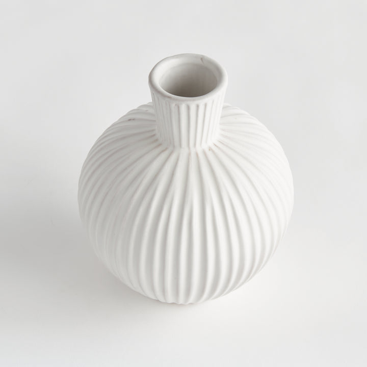 Angled view of a white terracotta vase with an open neck, rounded shoulders and deeply ribbed circular body. Transitional