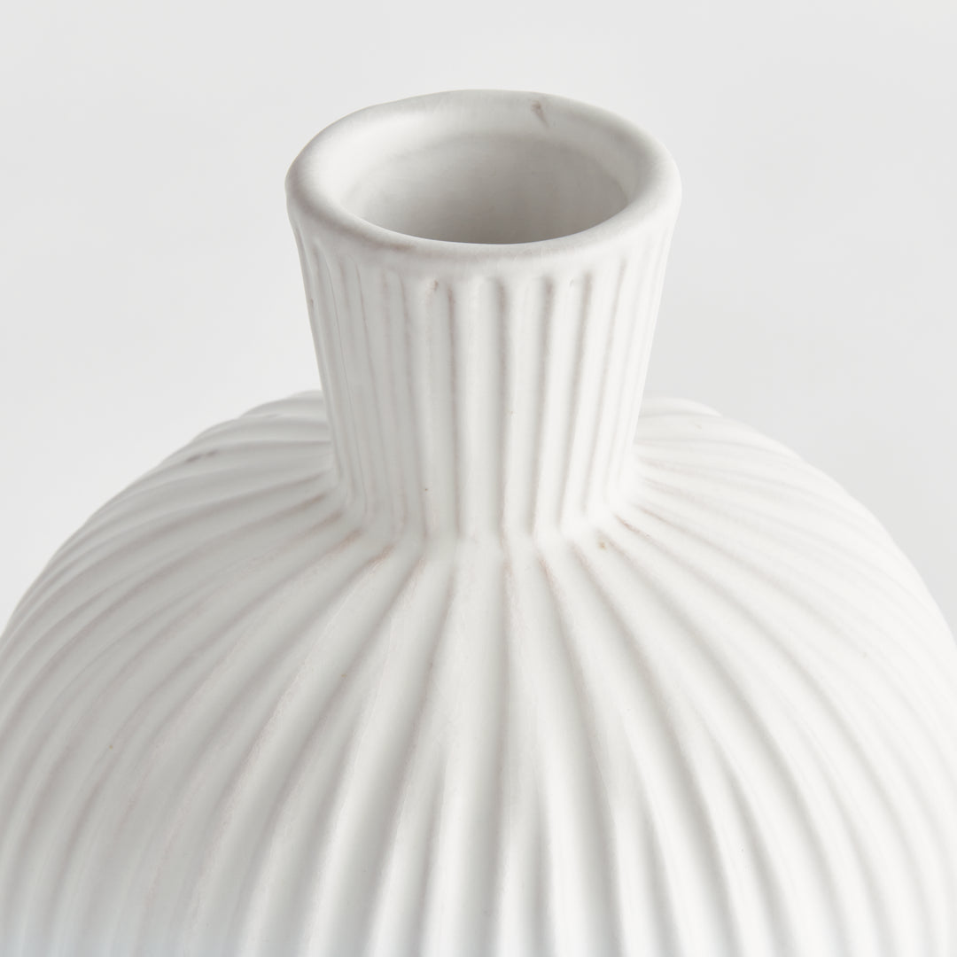 Close detail of a white terracotta vase neck and shoulder, showing the open mouth and vertical ribbed relief. Transitional