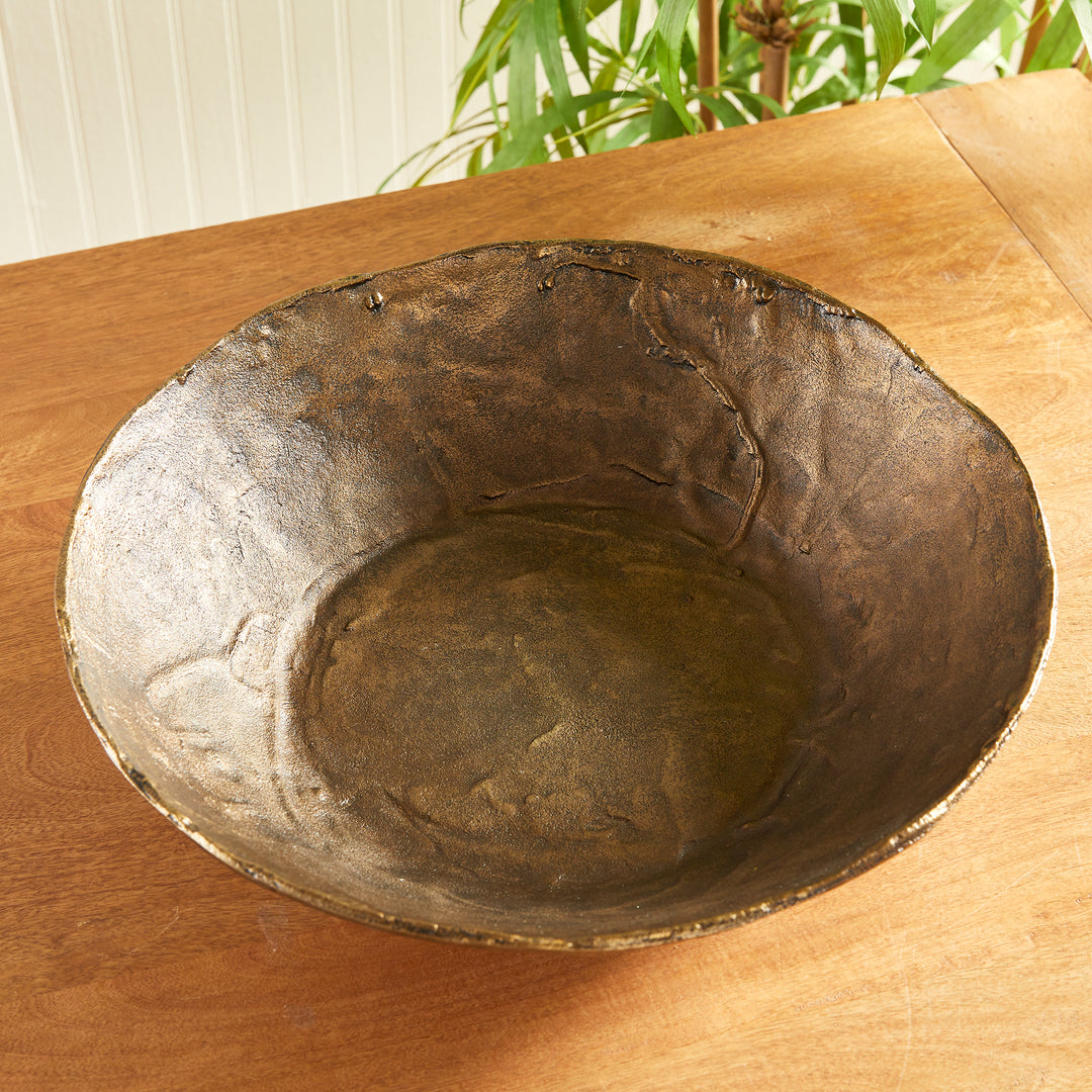 Overhead view of antique brass decorative aluminum bowl with textured interior and irregular rim on tabletop, Modern Organic