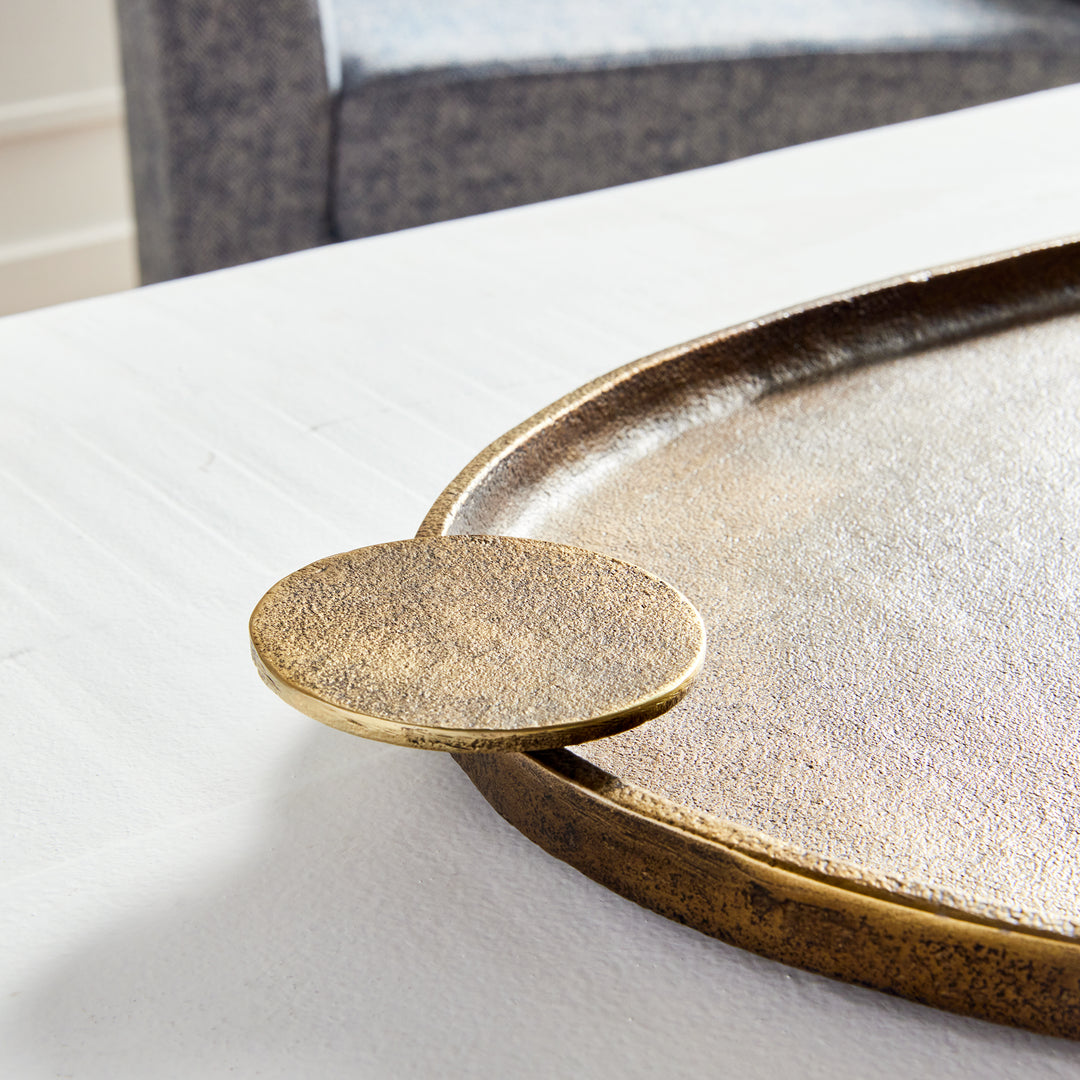 Close-up of antique brass aluminum decorative tray with textured finish, raised rim, and round handle detail – Transitional.