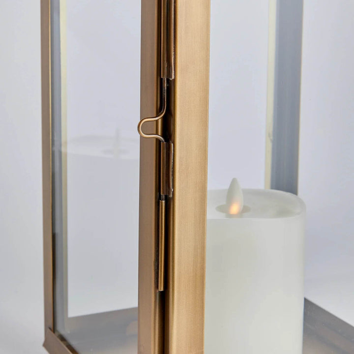 Close-up of glass lantern hinge and latch in antique brass finish, showing LED candle through clear glass panel – Transitional Decorative Accent