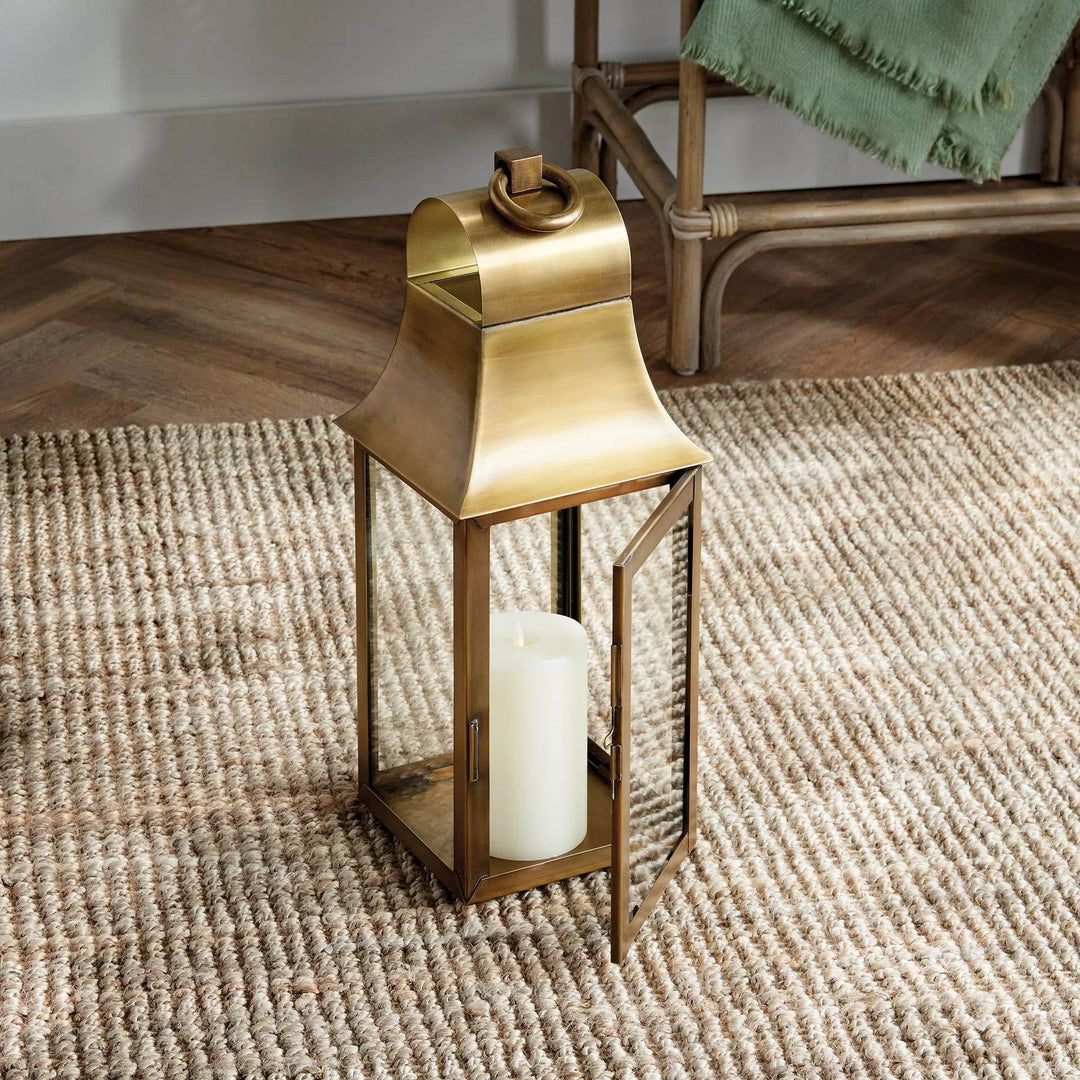 Two antique brass lanterns styled together on woven rug, each with LED candle, adding warm decorative glow – Transitional Decorative Lighting
