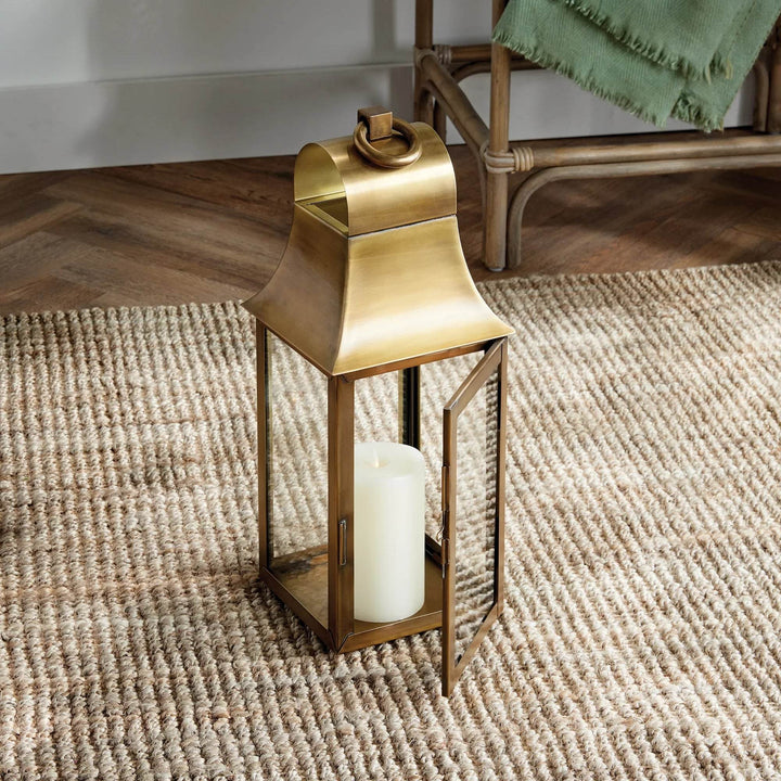 Two antique brass lanterns styled together on woven rug, each with LED candle, adding warm decorative glow – Transitional Decorative Lighting