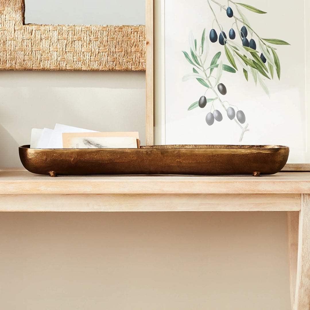Antique brass narrow decorative bowl styled on console table with artwork and decor creating a linear focal point modern organic interior